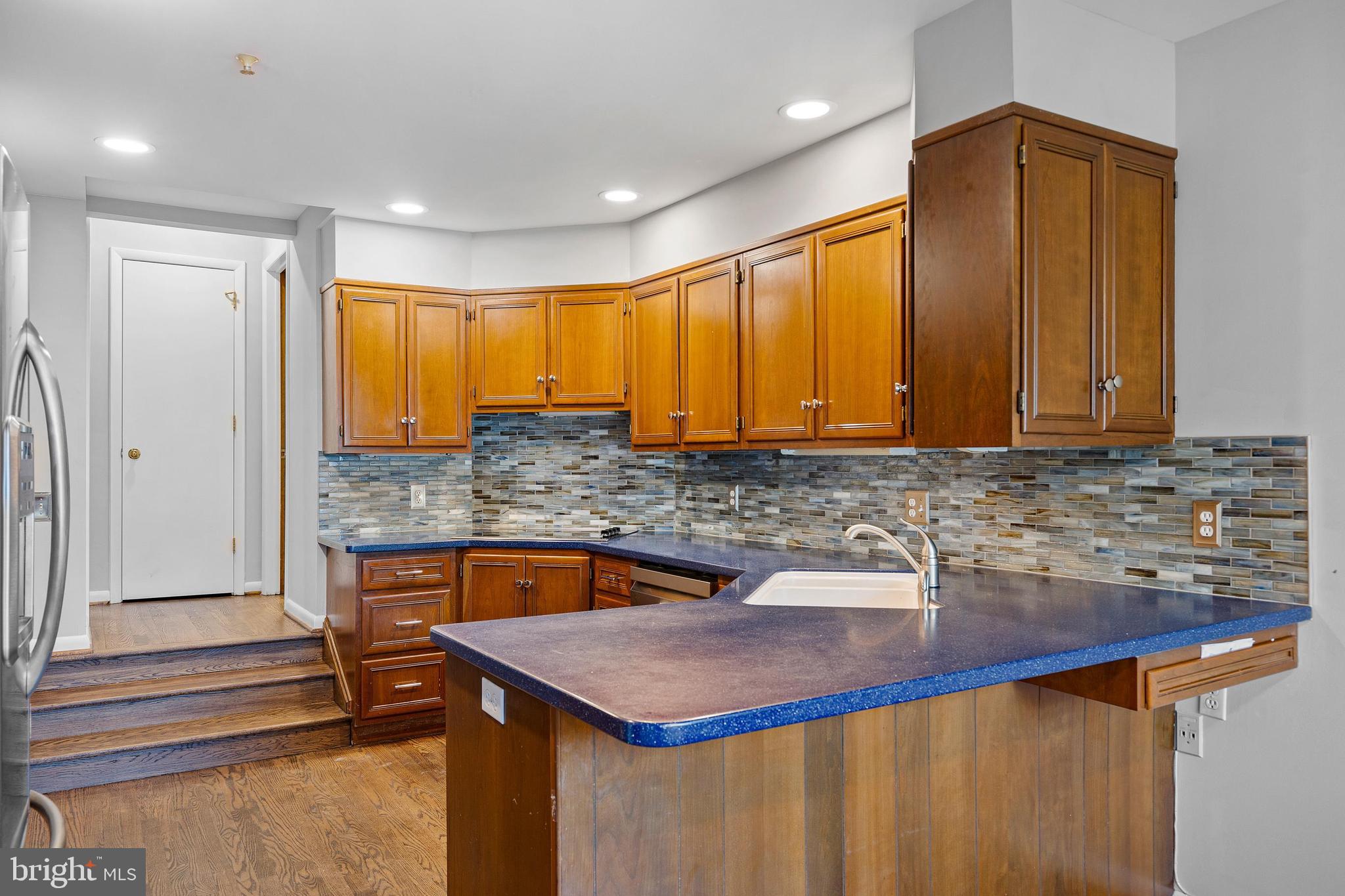 10 Brandywine Falls Road, Unit C010 Wilmington, DE 19806 - Photo 6 of 29 a kitchen that has a sink a microwave oven a stove and white cabinets with wooden floor