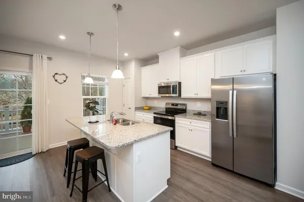 a kitchen with stainless steel appliances a dining table chairs refrigerator microwave and cabinets