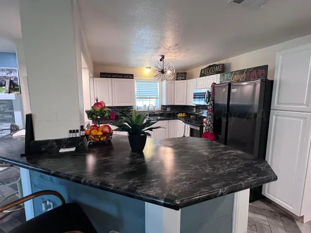 a kitchen with a sink a refrigerator and chairs