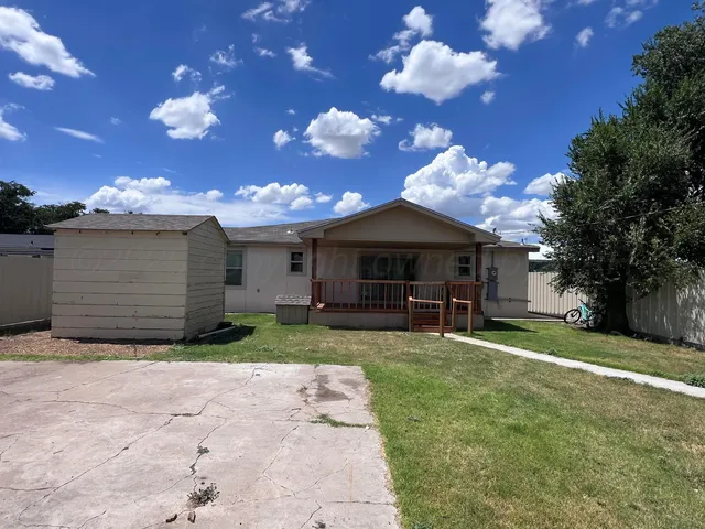 a view of a house with a yard and large tree