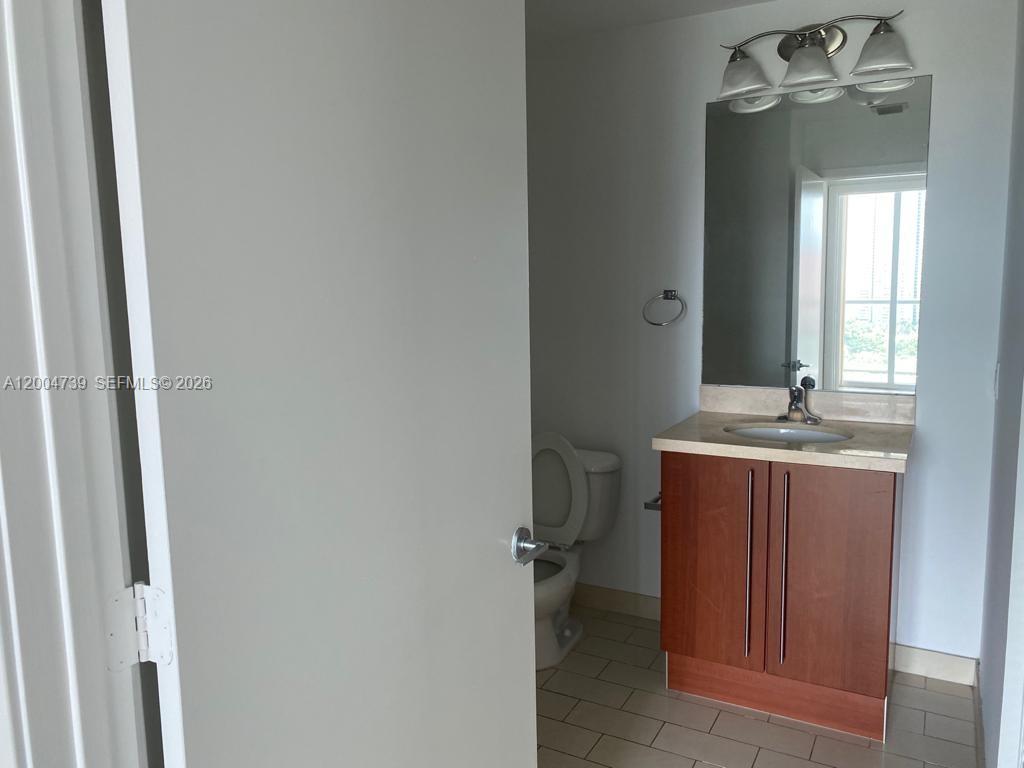 79 Southwest 12th Street, Unit 2403S Miami, FL 33130 - Photo 11 of 12 a bathroom with a granite countertop sink a toilet and mirror