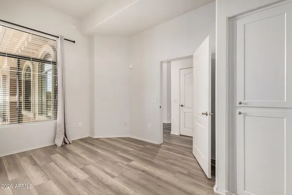 a view of empty room with wooden floor and fan
