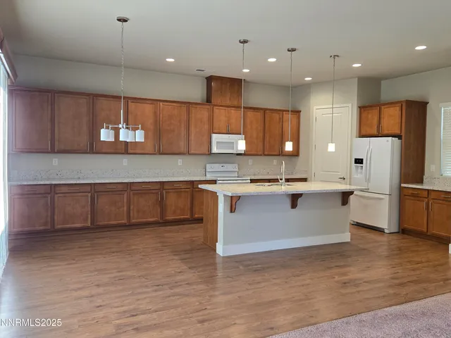 a large kitchen with stainless steel appliances granite countertop a stove a sink dishwasher a microwave oven and a refrigerator with wooden floor