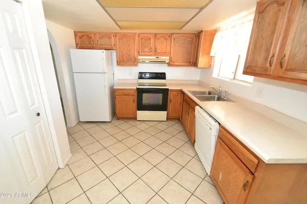 a kitchen with a sink a stove top oven cabinets a counter top space and a window