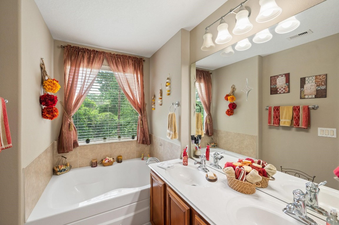 13600 Breton Ridge Street, Unit 25E Houston, TX 77070 - Photo 19 of 39 a bathroom with a sink vanity tub and a window