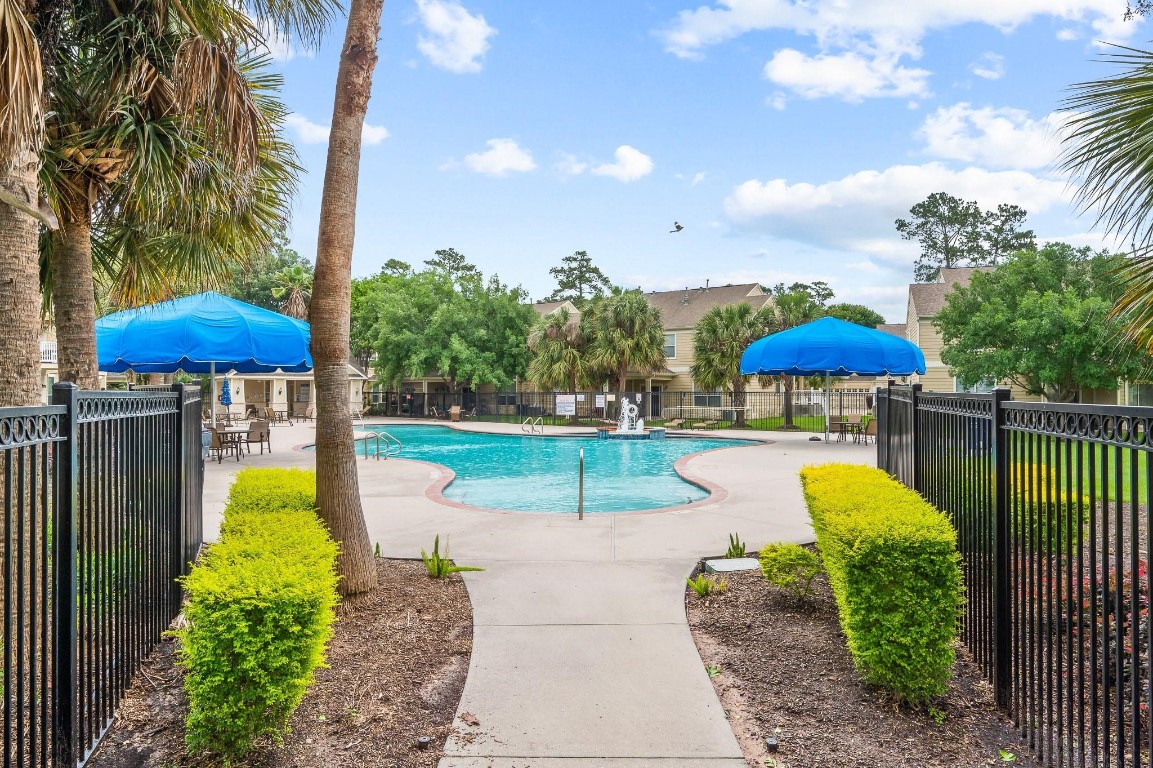 13600 Breton Ridge Street, Unit 25E Houston, TX 77070 - Photo 37 of 39 a view of a swimming pool with a table and chairs under an umbrella