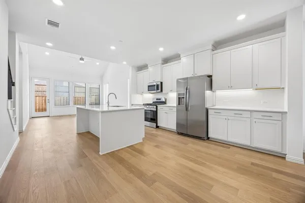 a large kitchen with stainless steel appliances granite countertop a large counter top a sink and a refrigerator