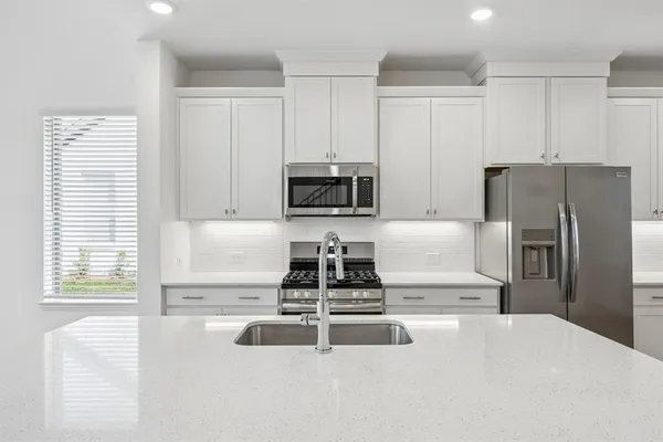 a kitchen with granite countertop a refrigerator and a stove top oven