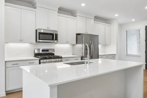 a kitchen with stainless steel appliances a stove a sink a refrigerator a microwave and cabinets