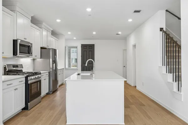 a kitchen with kitchen island a sink stainless steel appliances and cabinets