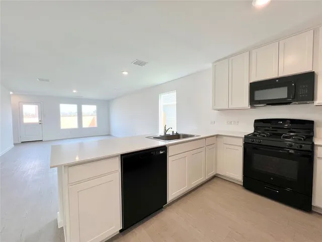 a kitchen with granite countertop white cabinets and stainless steel appliances