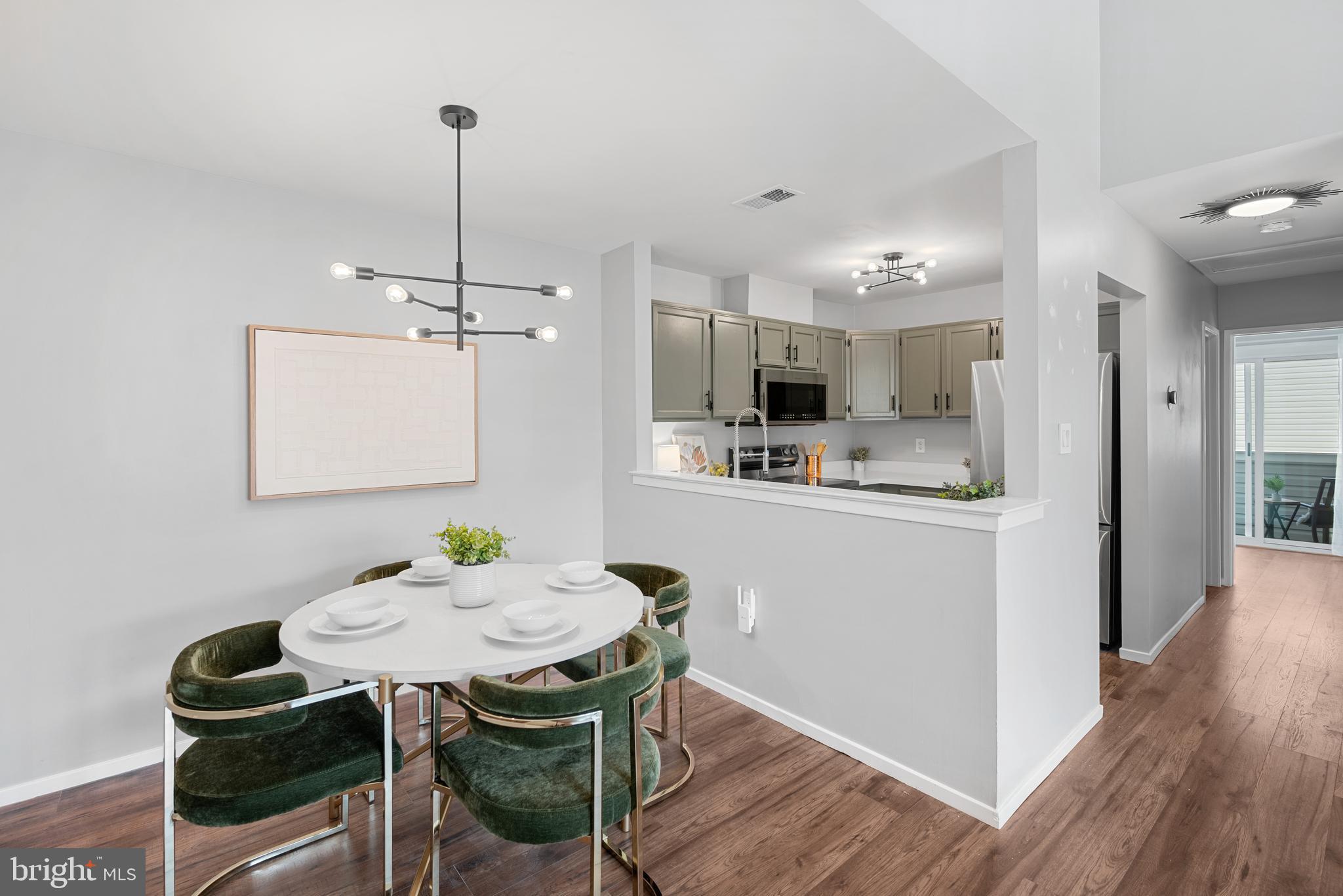 7826 Harrowgate Circle, Unit D Springfield, VA 22152 - Photo 6 of 21 a kitchen with kitchen island a dining table chairs and white cabinets