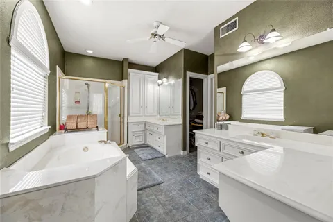 a large white bathroom with a large tub sink vanity and granite