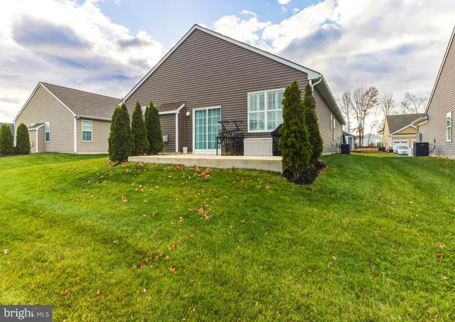 a view of a house next to a big yard and large trees
