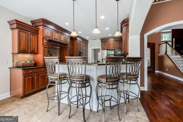 a kitchen with stainless steel appliances kitchen island granite countertop a table chairs and a refrigerator