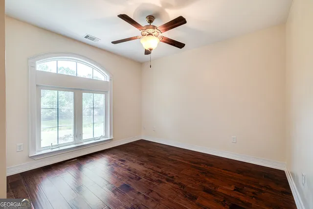 an empty room with wooden floor and windows