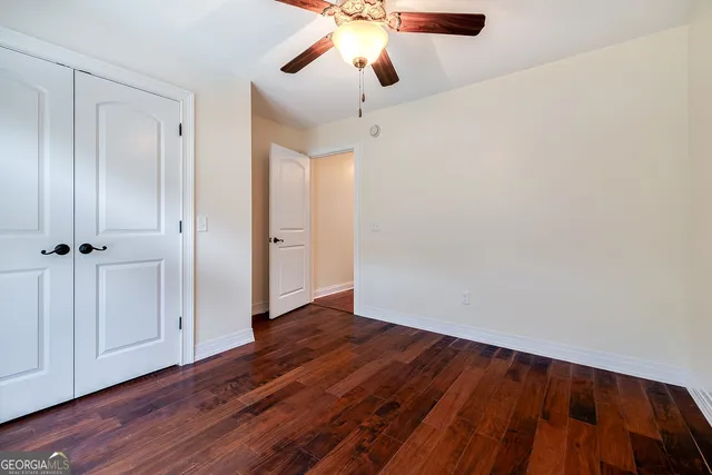 an empty room with wooden floor fan and window