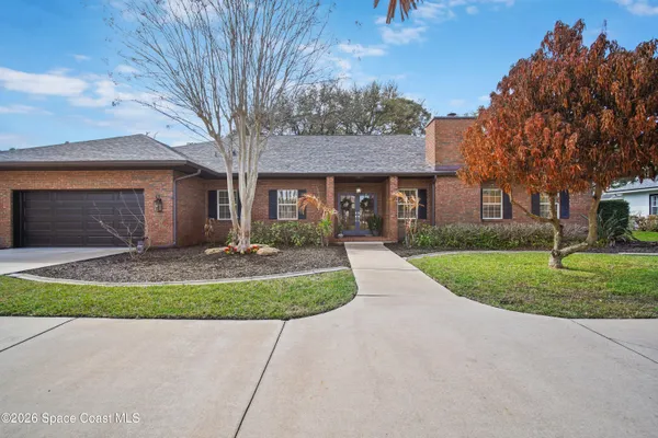 a front view of a house with a garden and trees