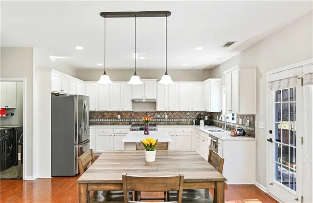a kitchen with a refrigerator a stove cabinets and wooden floor