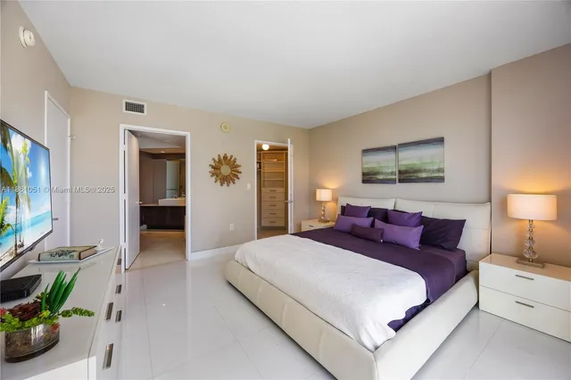 a spacious bedroom with a bed and a flat screen television