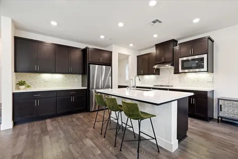 a kitchen with stainless steel appliances kitchen island granite countertop a sink counter space and wooden floor