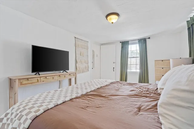 a bedroom with a bed and a flat screen tv on dresser