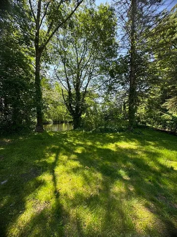 a view of a white house next to a yard with big trees
