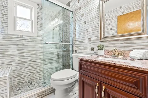 a bathroom with a granite countertop toilet sink and mirror
