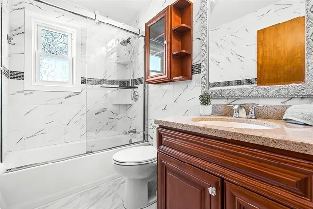 a bathroom with a granite countertop sink toilet and shower