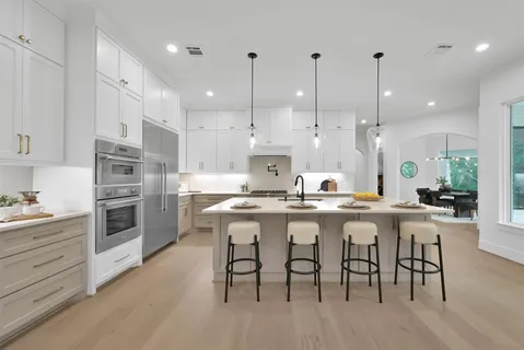 a kitchen with stainless steel appliances granite countertop a sink a stove a refrigerator and island with wooden floor