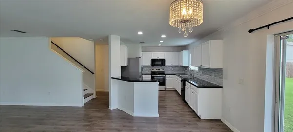 a kitchen with stainless steel appliances granite countertop a refrigerator a stove a sink and a dining table with wooden floor