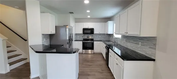 a kitchen with stainless steel appliances granite countertop a sink and a refrigerator