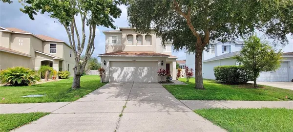 a front view of a house with a garden and trees