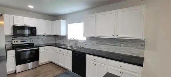 a kitchen with granite countertop white cabinets stainless steel appliances and a sink