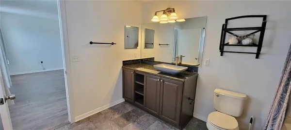 a bathroom with a granite countertop toilet sink and mirror