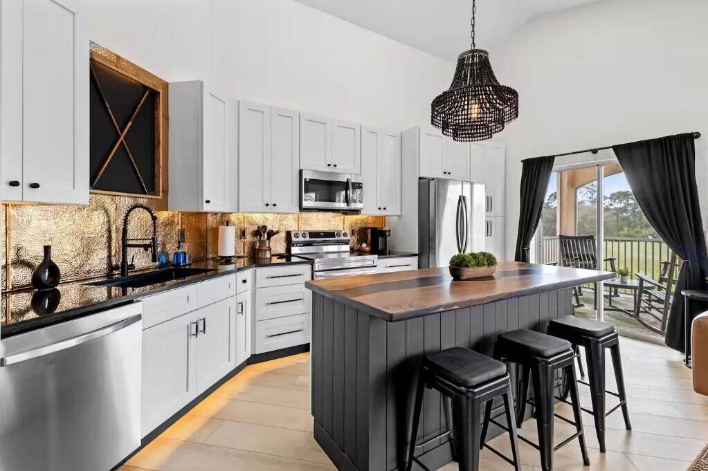 9843 Perfect Drive, Unit A Port St. Lucie, FL 34986 - Photo 6 of 8 a kitchen with stainless steel appliances granite countertop a sink a stove and chairs