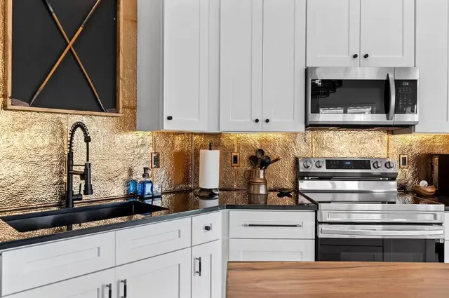 a kitchen with stainless steel appliances granite countertop a sink a stove and microwave