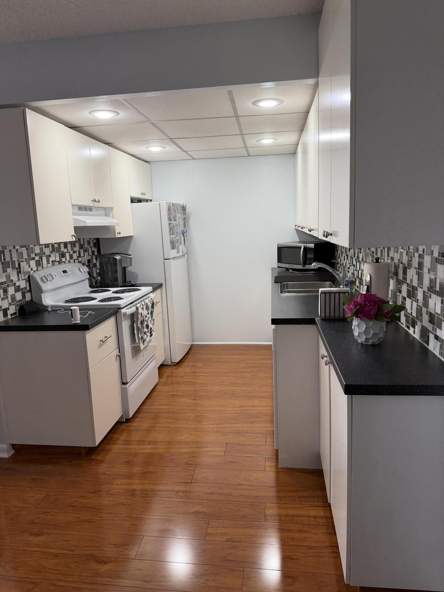 3062 Ainslie Drive Boca Raton, FL 33434 - Photo 8 of 27 a kitchen with stainless steel appliances a sink stove and refrigerator