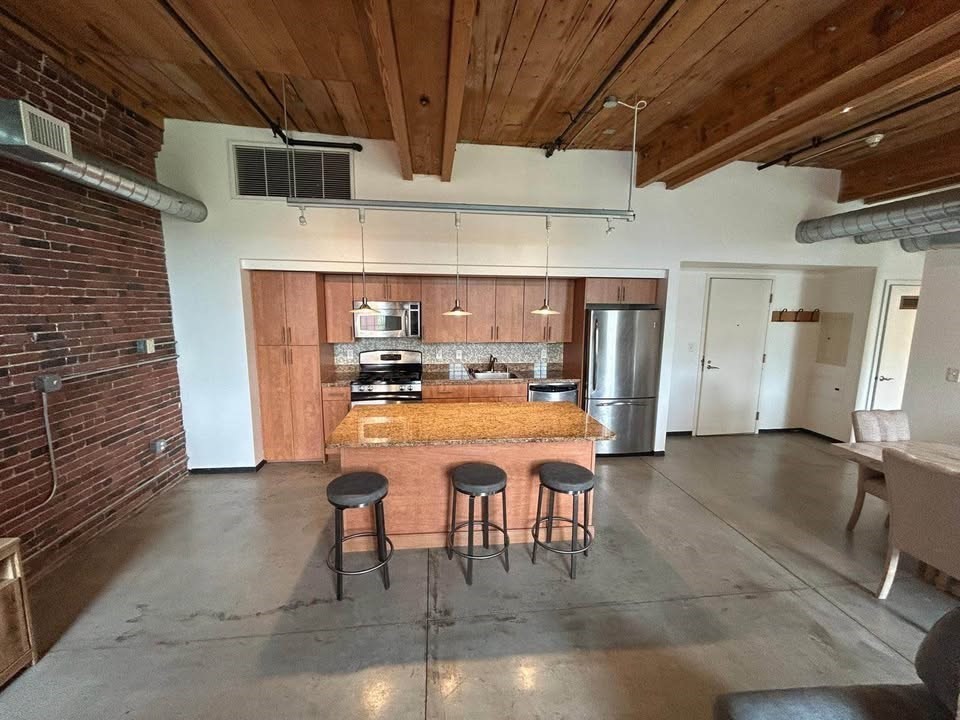 130 John Street, Unit 213 Lowell, MA 01852 - Photo 15 of 17 a room with stainless steel appliances kitchen island granite countertop furniture and a fireplace