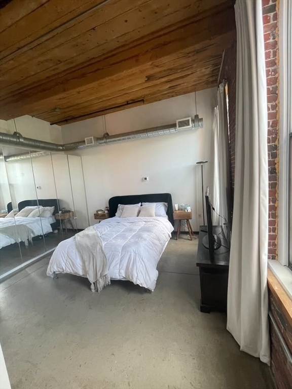 130 John Street, Unit 213 Lowell, MA 01852 - Photo 8 of 17 a spacious bedroom with a bed and a window