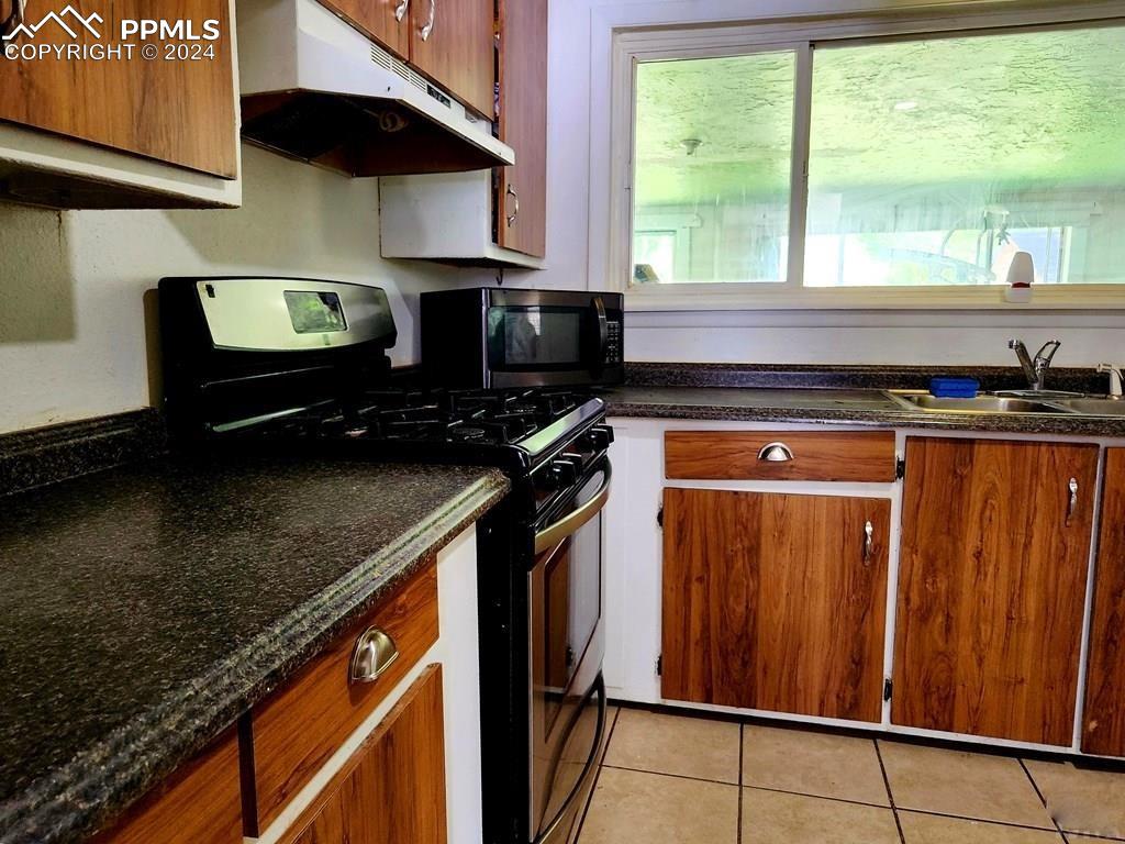 1509 Kickapoo Road Pueblo, CO 81001 - Photo 6 of 24 a kitchen with stainless steel appliances granite countertop a stove a sink and a microwave