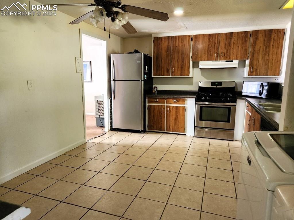 1509 Kickapoo Road Pueblo, CO 81001 - Photo 8 of 24 a kitchen with granite countertop a refrigerator and a stove top oven