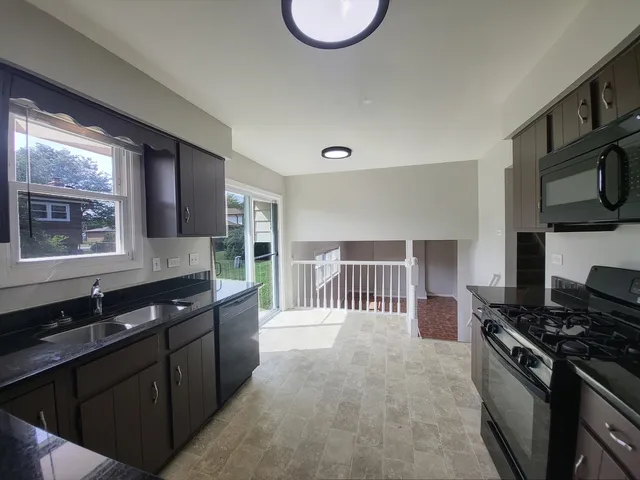 a kitchen with stainless steel appliances granite countertop a stove a sink and a microwave