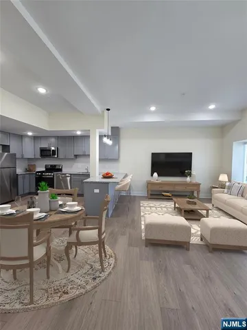 a living room with furniture a flat screen tv and kitchen view