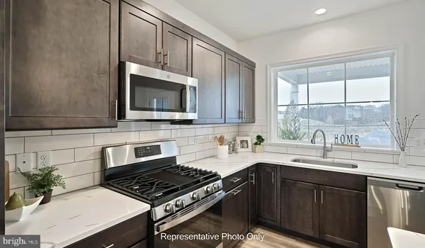 a kitchen with granite countertop a stove a sink and a microwave