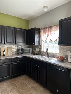 a kitchen with granite countertop stainless steel appliances a sink window and cabinets