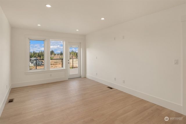 a view of an empty room with wooden floor and kitchen