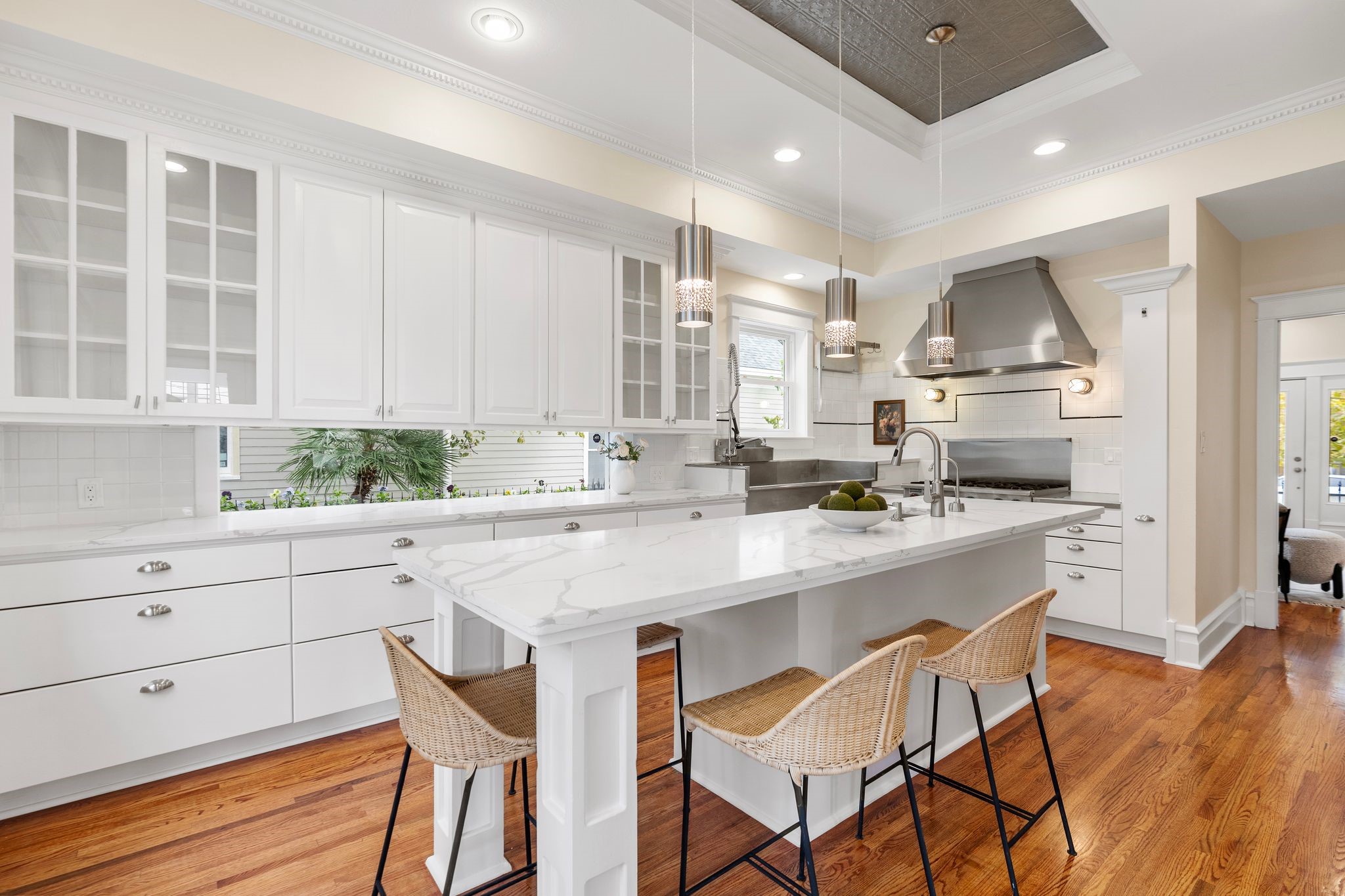 607 Harvard Street Houston, TX 77007 - Photo 16 of 50 Updated in 2025 with new quartz counters, the large windowed kitchen is a chef’s wonderland filled with custom cabinetry, tile backsplashes, and tall tin ceilings trimmed with crown molding and recessed lighting.