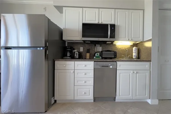 a kitchen with white cabinets and stainless steel appliances