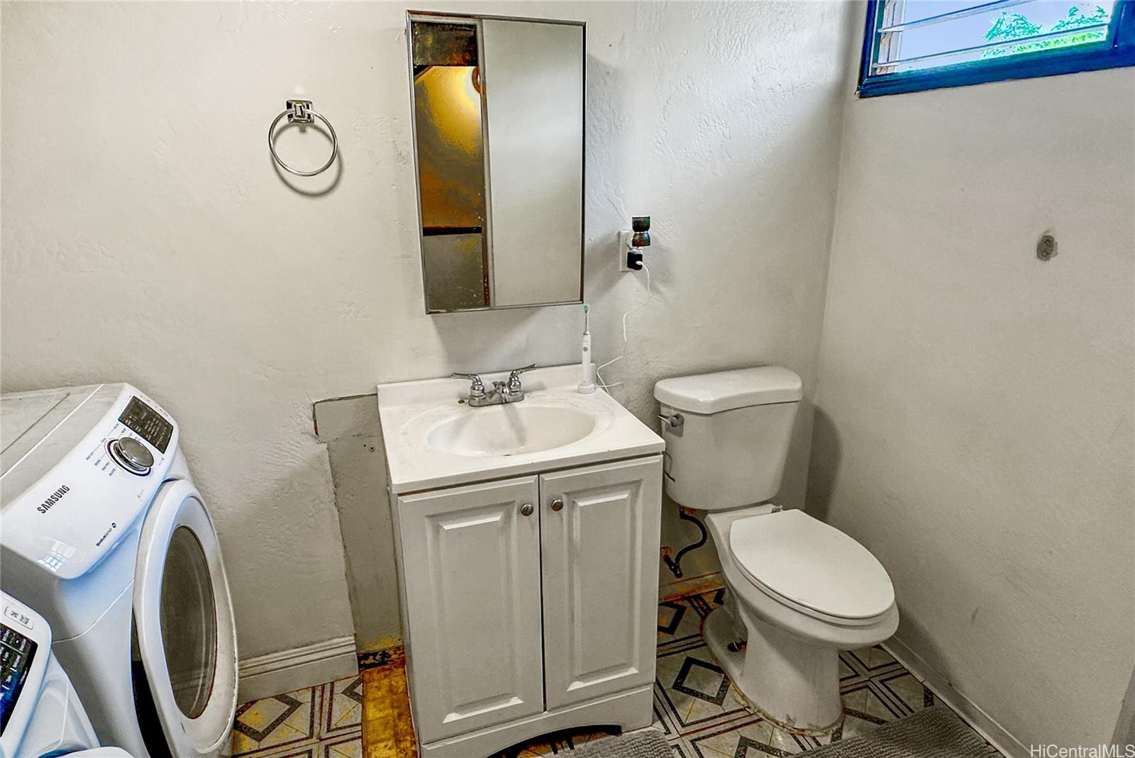 87217 Helelua Street, Unit 1 Waianae, HI 96792 - Photo 10 of 15 a bathroom with a toilet sink vanity and mirror